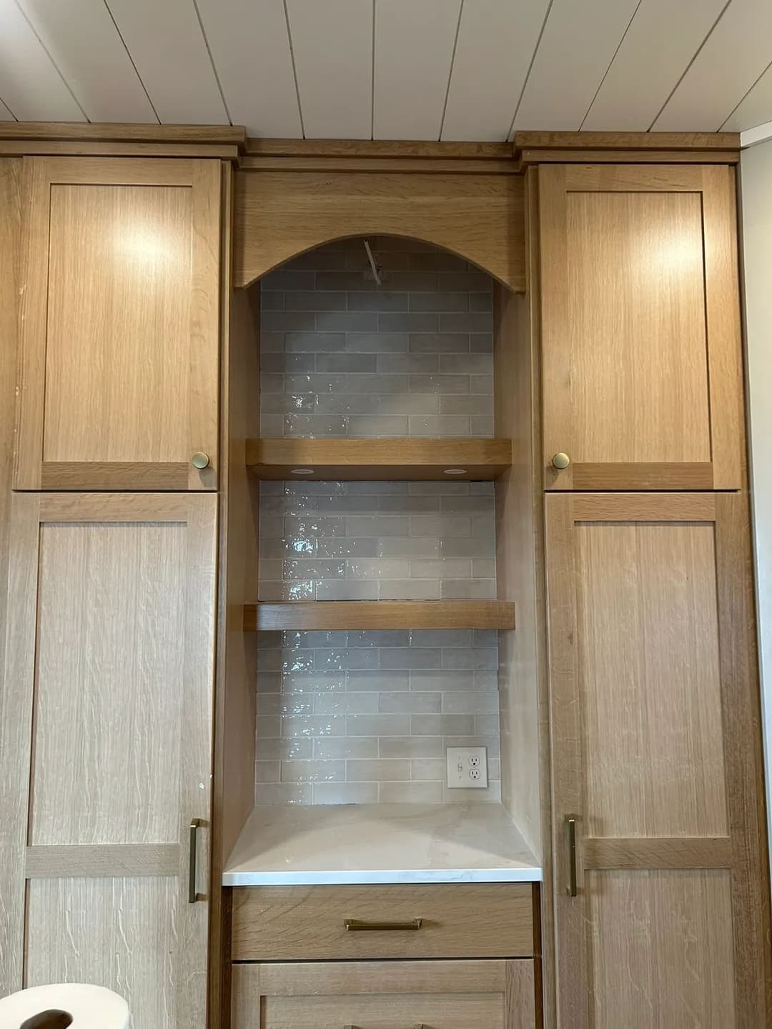 Custom wood cabinetry with arch detail and open shelves in a modern kitchen design.