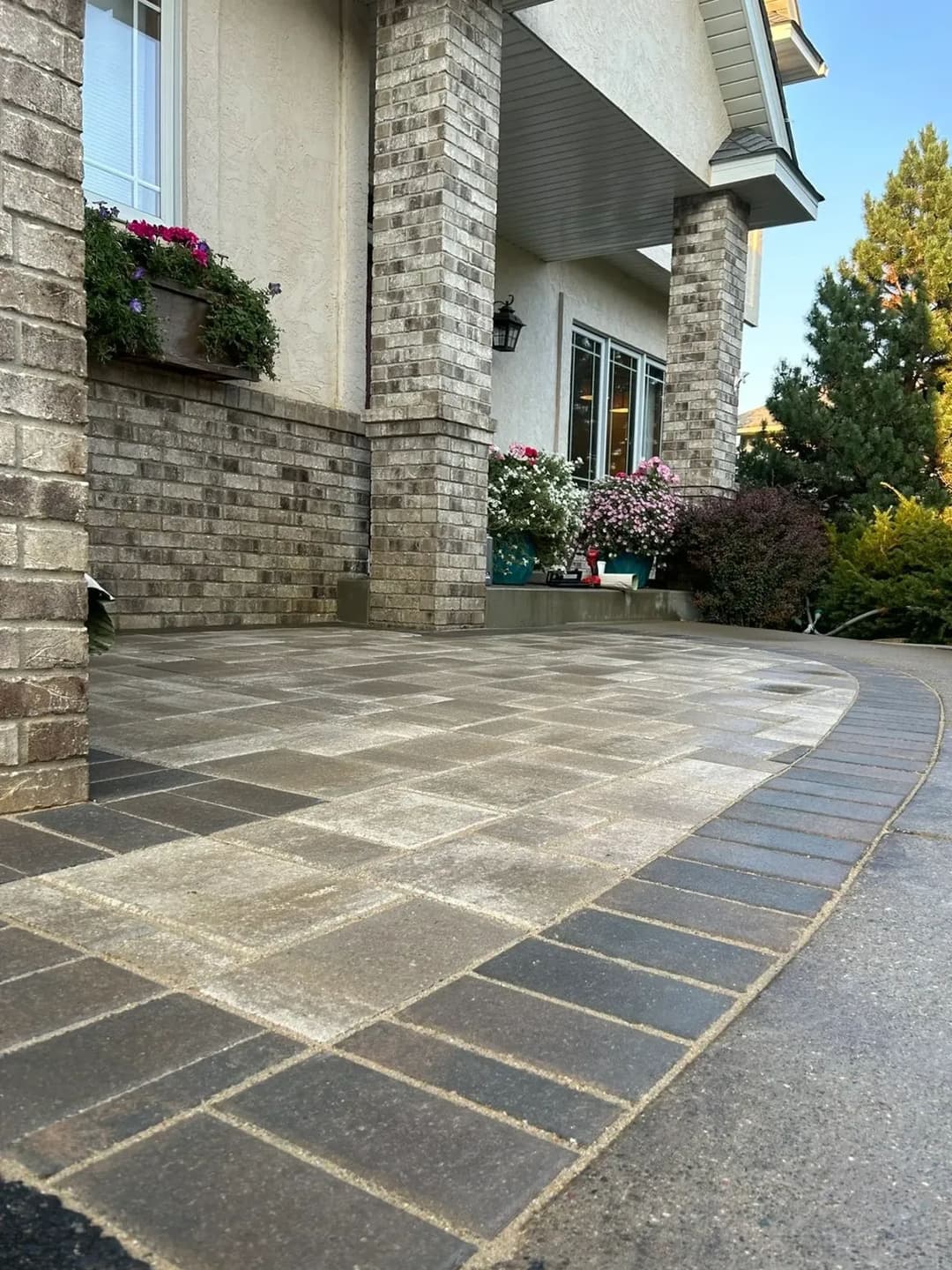 Beautiful paved walkway leading to a home entrance, featuring decorative flower planters.