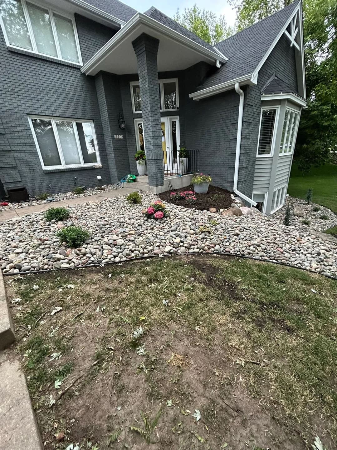 Front yard landscaping featuring a stone garden, flowers, and a modern home entrance.