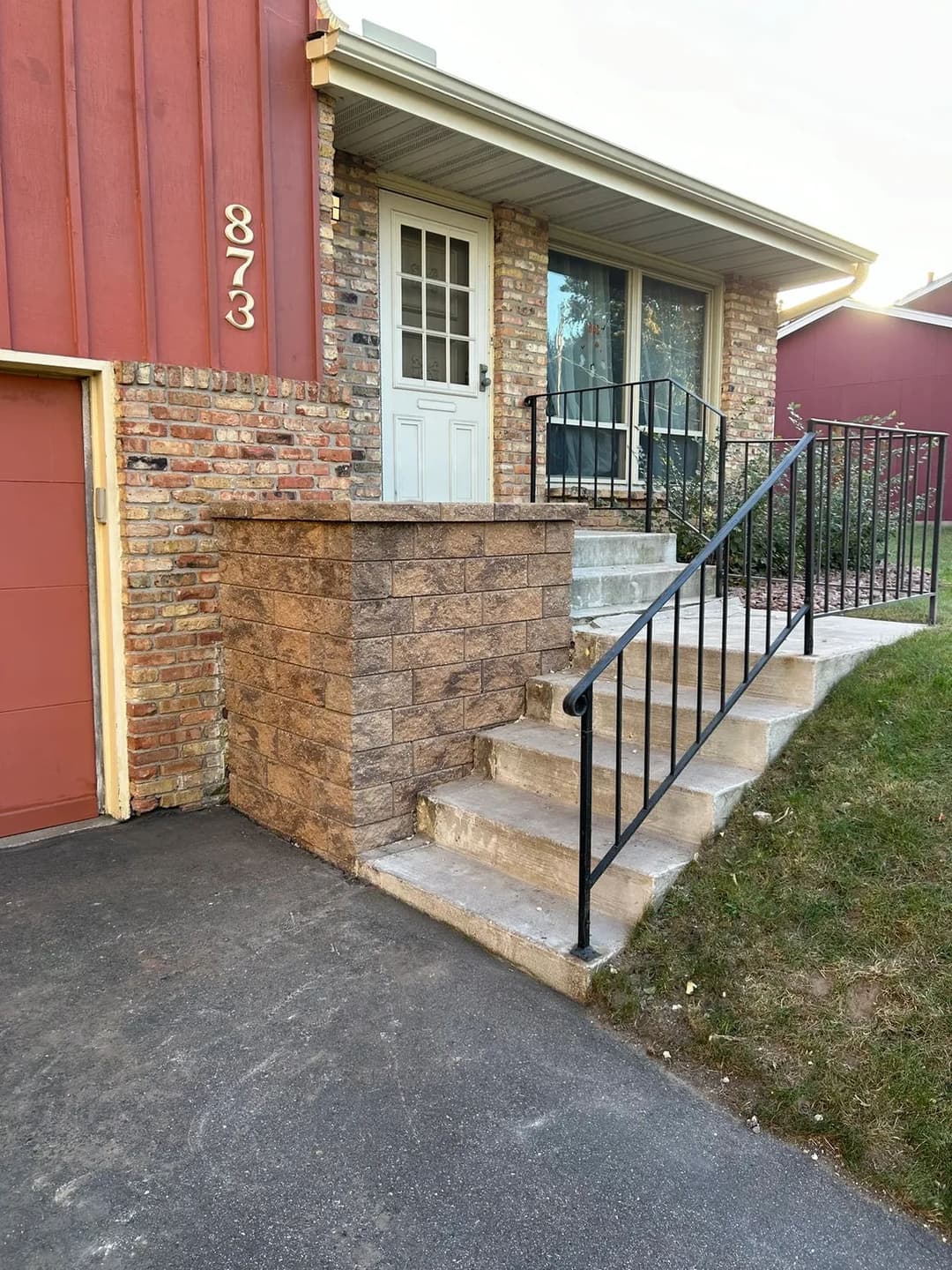 Front entrance of a house with stone steps, railings, and garage. Address: 873.